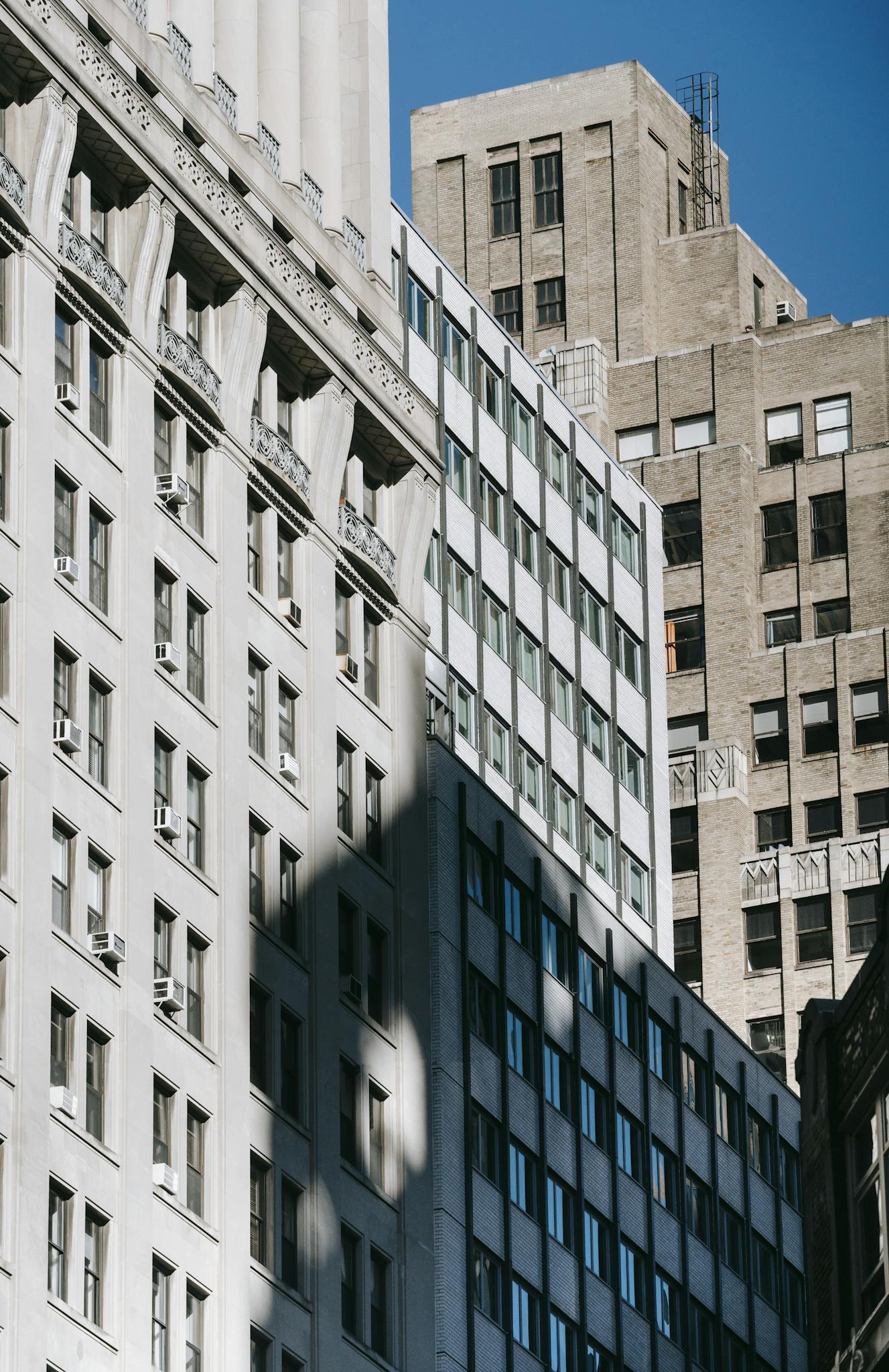 Low-angle view of urban high-rise buildings against a clear blue sky.